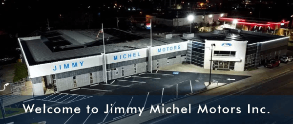 Exterior view of Jimmy Michel Motors dealership at night, also welcome to Jimmy Michel Motors Inc written on it.